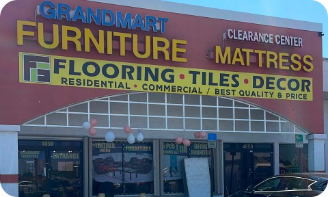 Large commercial vinyl banner displayed on a storefront promoting furniture and decor